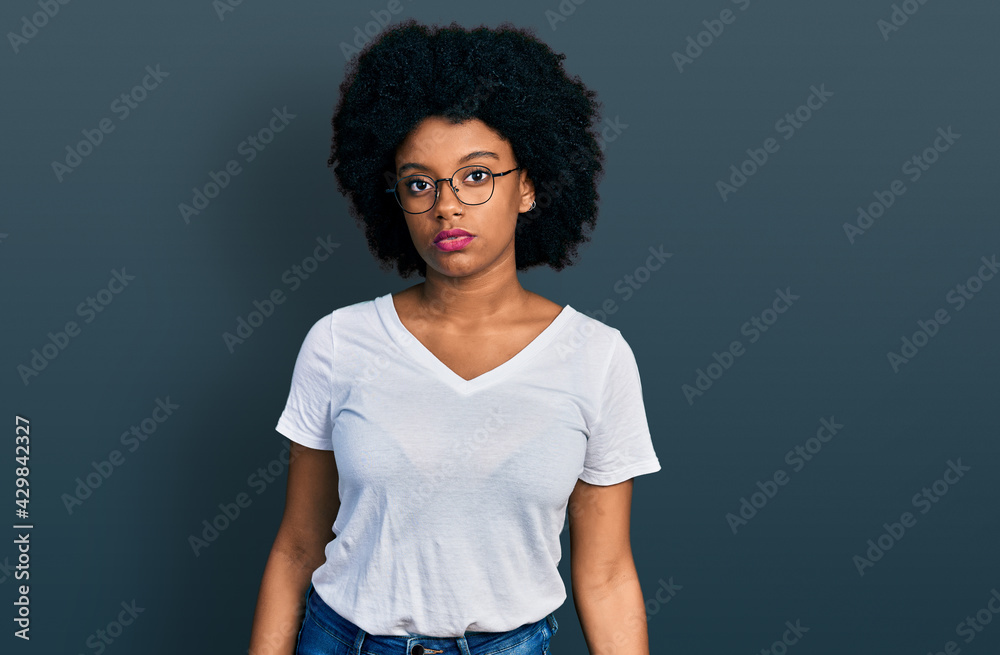 Young african american woman wearing casual white t shirt relaxed with serious expression on face. simple and natural looking at the camera. Young african american woman wearing casual white t shirt relaxed with serious expression on face. simple and natural looking at the camera.