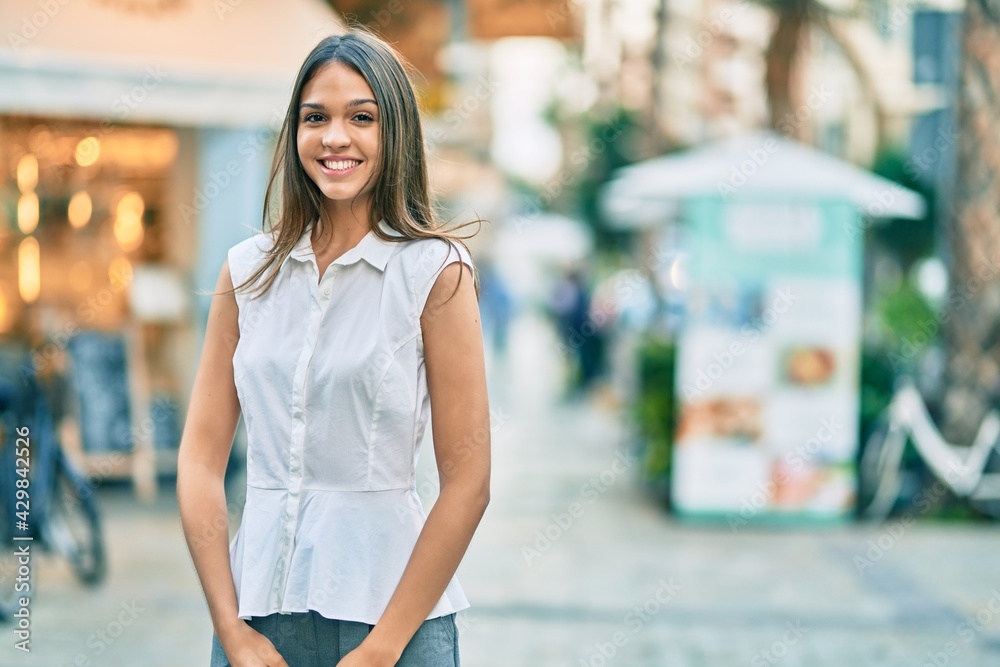 Beautiful latin teenager girl smiling happy standing at the city.
