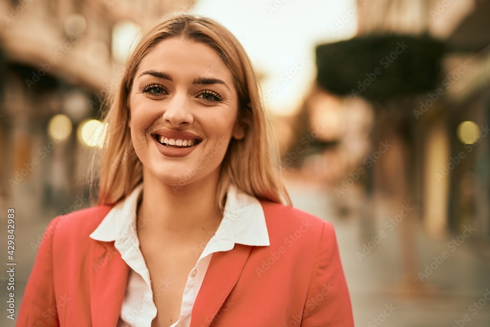 Young blonde businesswoman smiling happy standing at the city.