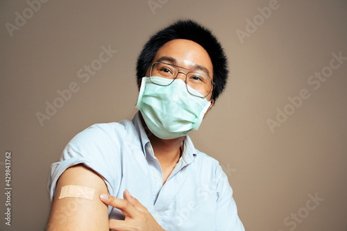 Asian man got covid-19 vaccine. Young asian male looking at his arm happily after getting his first vaccine shot. Teenage received his first vaccine dose,Man cured his illness and disease condition