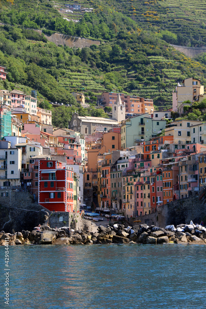 Riomaggiore Italy is a very colorful town that hangs on the mountainside with many vineyards and is one of five towns that make up the cinque terre region.