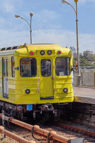 A bright yellow subway train carriage on the platform of a metro bridge in Kyiv.