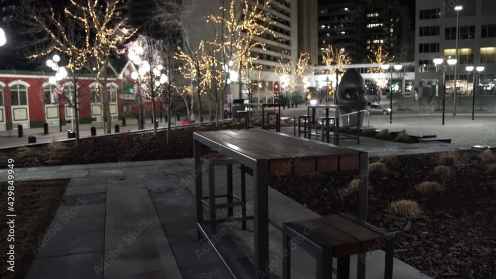 Calgary Alberta Canada, April 7 2021: Aerial rise over outdoor patio furniture at an empty downtown public square at night in a Canadian City.
Calgary Alberta Canada, April 7 2021: Aerial rise over outdoor patio furniture at an empty downtown public square at night in a Canadian City.