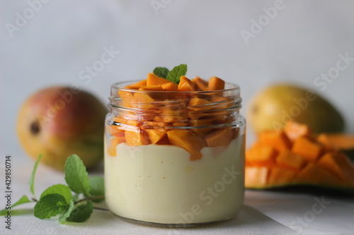 Vanilla custard topped with fresh cut mangoes served in a jar. photo