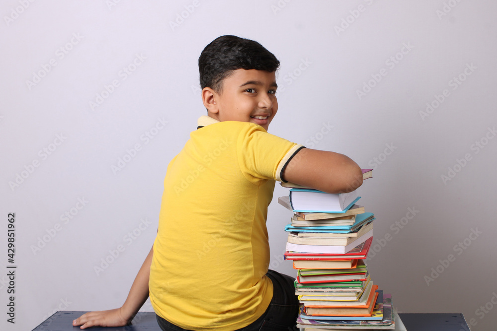 indian school boy or scholar kid with stack of books indian school boy or scholar kid with stack of books