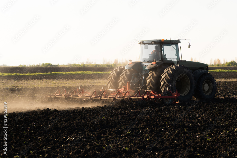 Fototapeta premium Tractor is preparing the land at dusk
