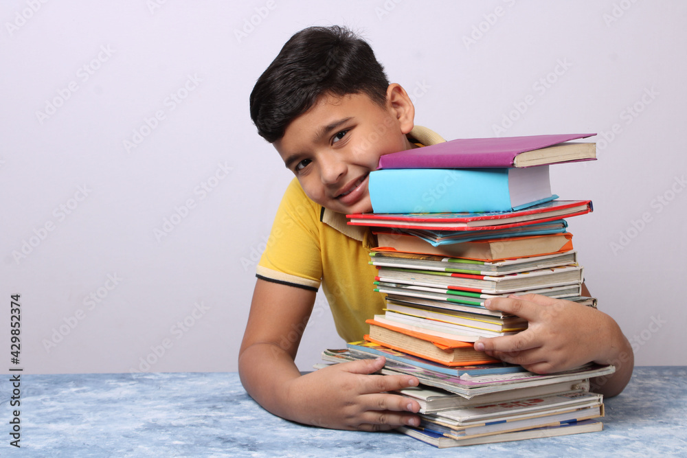 indian school boy or scholar kid with stack of books indian school boy or scholar kid with stack of books