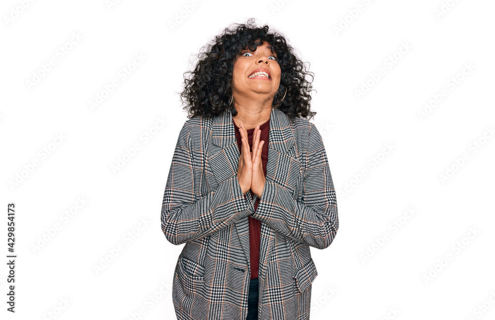 Young hispanic woman wearing business clothes begging and praying with hands together with hope expression on face very emotional and worried. begging. Young hispanic woman wearing business clothes begging and praying with hands together with hope expression on face very emotional and worried. begging.