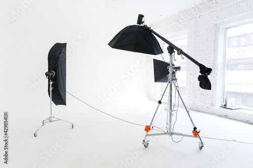 Empty photo studio with lighting equipment. Photographer workplace interior with professional tool set gear. Flash light white background scenes ready for studio shooting. Modern photographer studio