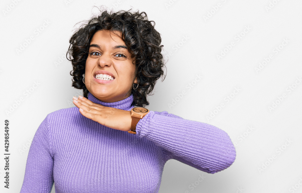 Young hispanic woman with curly hair wearing casual clothes cutting throat with hand as knife, threaten aggression with furious violence Young hispanic woman with curly hair wearing casual clothes cutting throat with hand as knife, threaten aggression with furious violence