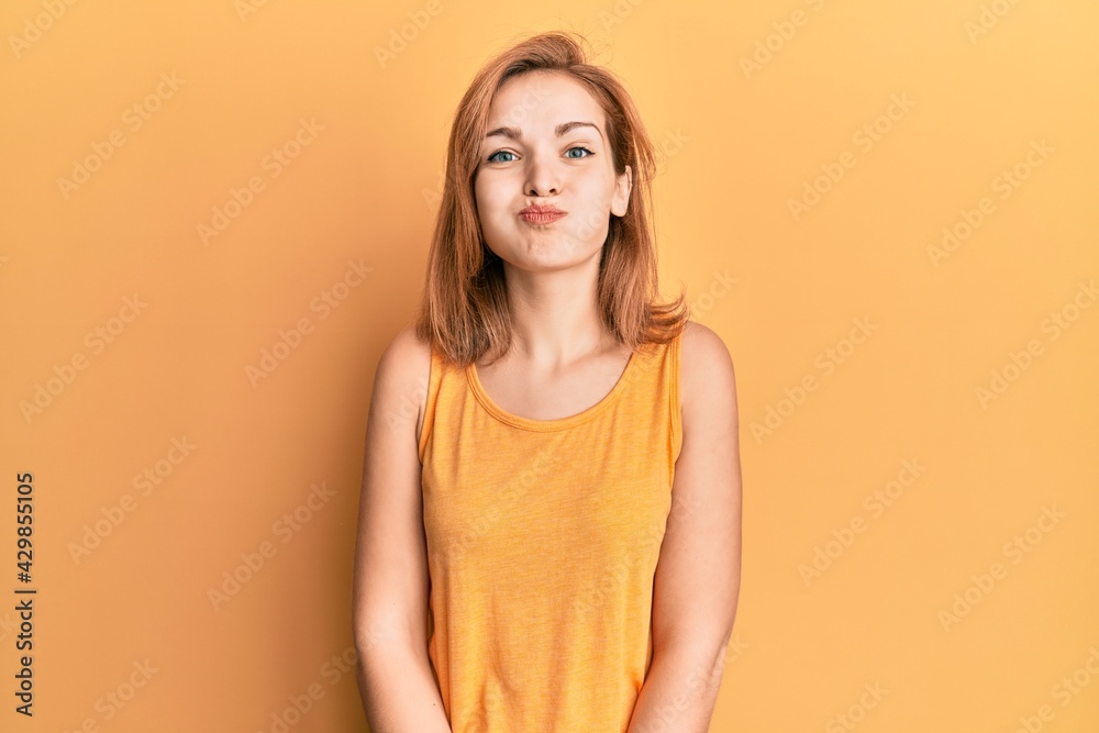 Young caucasian woman wearing casual style with sleeveless shirt puffing cheeks with funny face. mouth inflated with air, crazy expression. Young caucasian woman wearing casual style with sleeveless shirt puffing cheeks with funny face. mouth inflated with air, crazy expression.