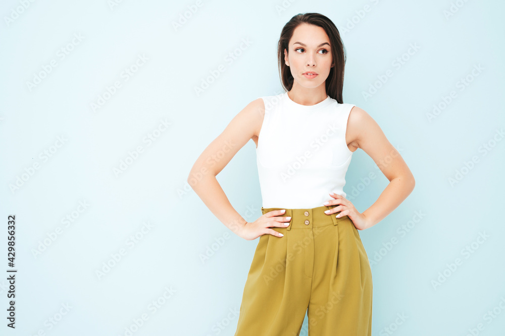 Young beautiful smiling female in trendy summer suit clothes. Sexy carefree woman posing near light blue wall in studio. Positive model having fun indoors. Cheerful and happy Young beautiful smiling female in trendy summer suit clothes. Sexy carefree woman posing near light blue wall in studio. Positive model having fun indoors. Cheerful and happy