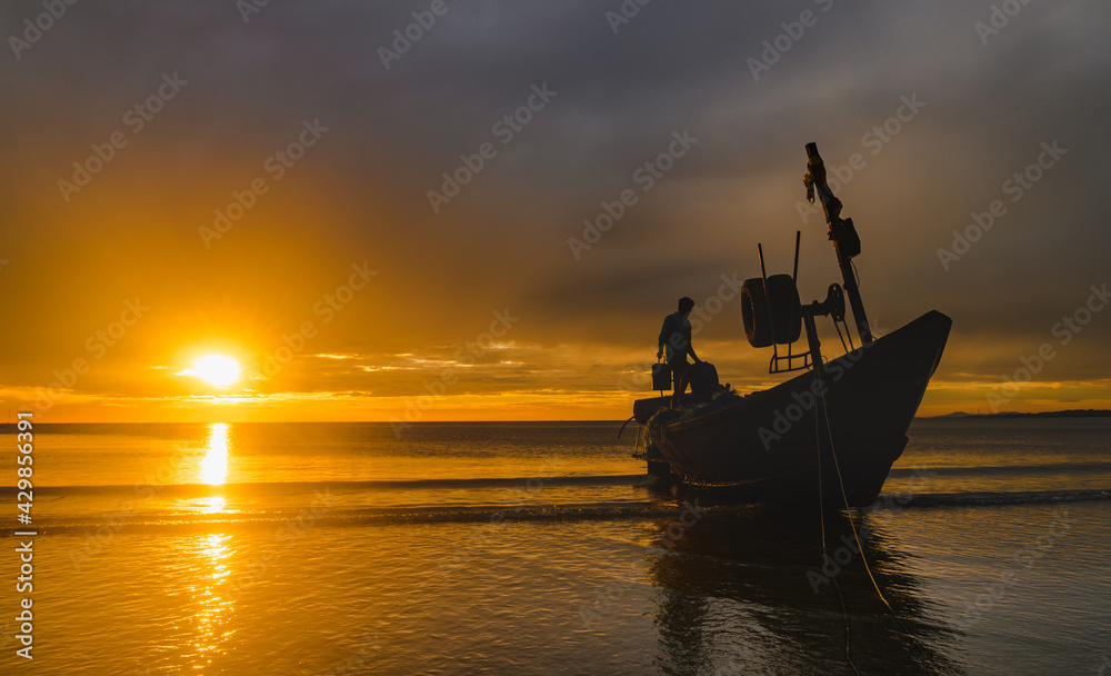 Silhouette of working fisherman and wooden boat.