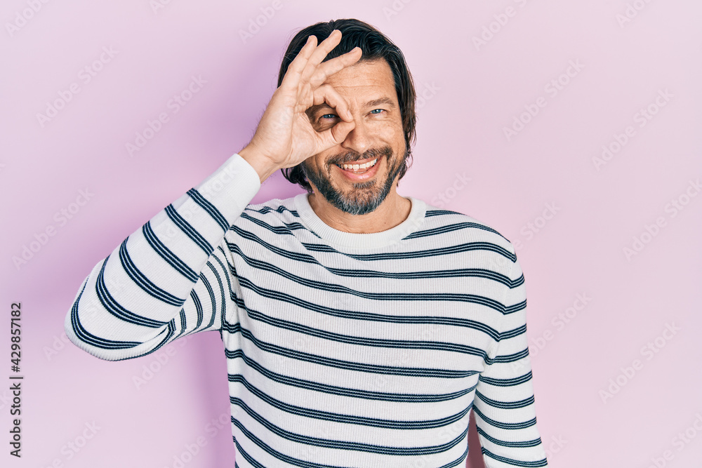 Middle age caucasian man wearing casual clothes doing ok gesture with hand smiling, eye looking through fingers with happy face. Middle age caucasian man wearing casual clothes doing ok gesture with hand smiling, eye looking through fingers with happy face.