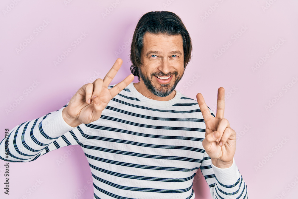 Fototapeta premium Middle age caucasian man wearing casual clothes smiling looking to the camera showing fingers doing victory sign. number two.