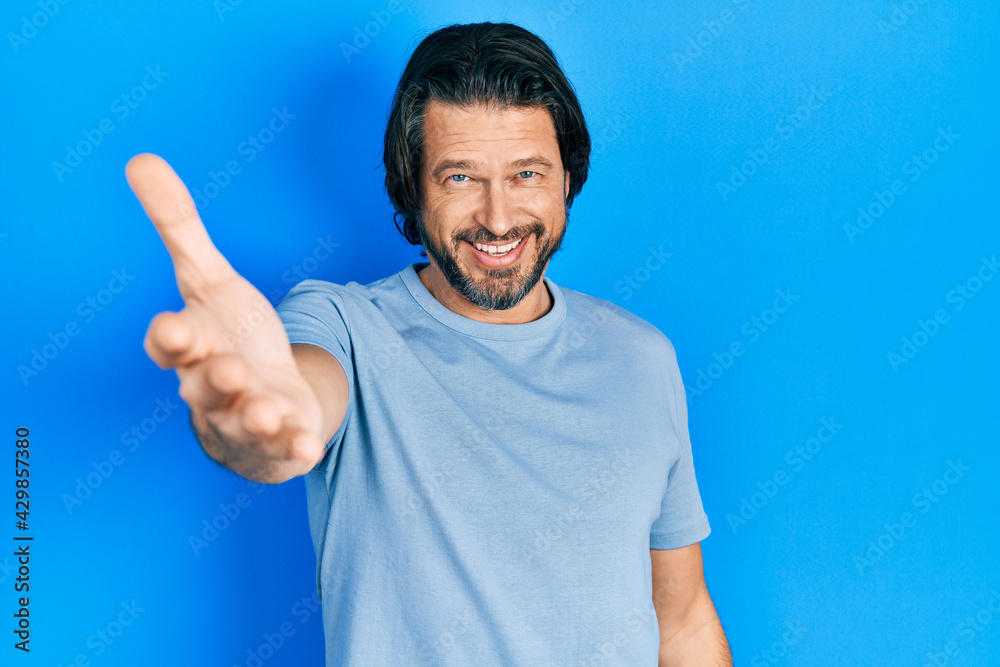Middle age caucasian man wearing casual clothes smiling friendly offering handshake as greeting and welcoming. successful business. Middle age caucasian man wearing casual clothes smiling friendly offering handshake as greeting and welcoming. successful business.