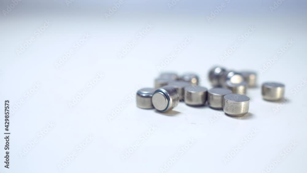 Close up on button battery. The batteries were scattered on the table. Truck shot from right to left. Close up on button battery. The batteries were scattered on the table. Truck shot from right to left.