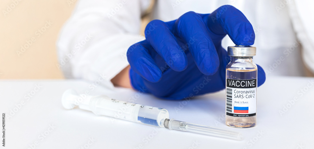 Russian coronavirus vaccine concept banner, vaccine vial with label, county flag, doctor in blue gloves Russian coronavirus vaccine concept banner, vaccine vial with label, county flag, doctor in blue gloves