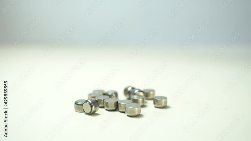 Close up on button battery. The batteries were scattered on the table. Tilt shot from top to bottom.