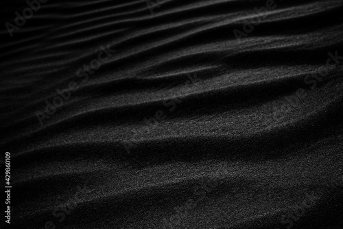 Black Sand dune. Black Sand beach macro photography. Background, texture, wave pattern of oceanic sand on the beach, black. Texture of beach sand. Black beach.