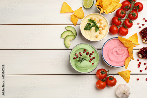 Flat lay composition with delicious hummuses on white wooden table. Space for text