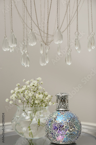 Stylish catalytic lamp with gypsophila on table in room. Cozy interior