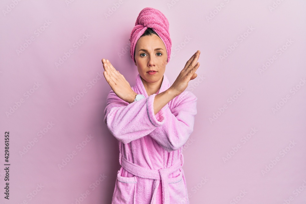Young blonde woman wearing shower towel cap and bathrobe rejection expression crossing arms doing negative sign, angry face Young blonde woman wearing shower towel cap and bathrobe rejection expression crossing arms doing negative sign, angry face