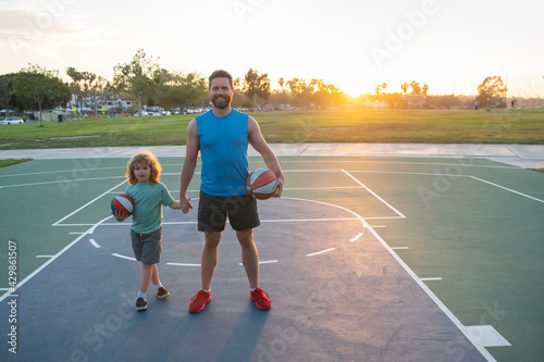Basketball game. Father and son training with basket ball on basketball court outdoor. Dad and child spending time together.