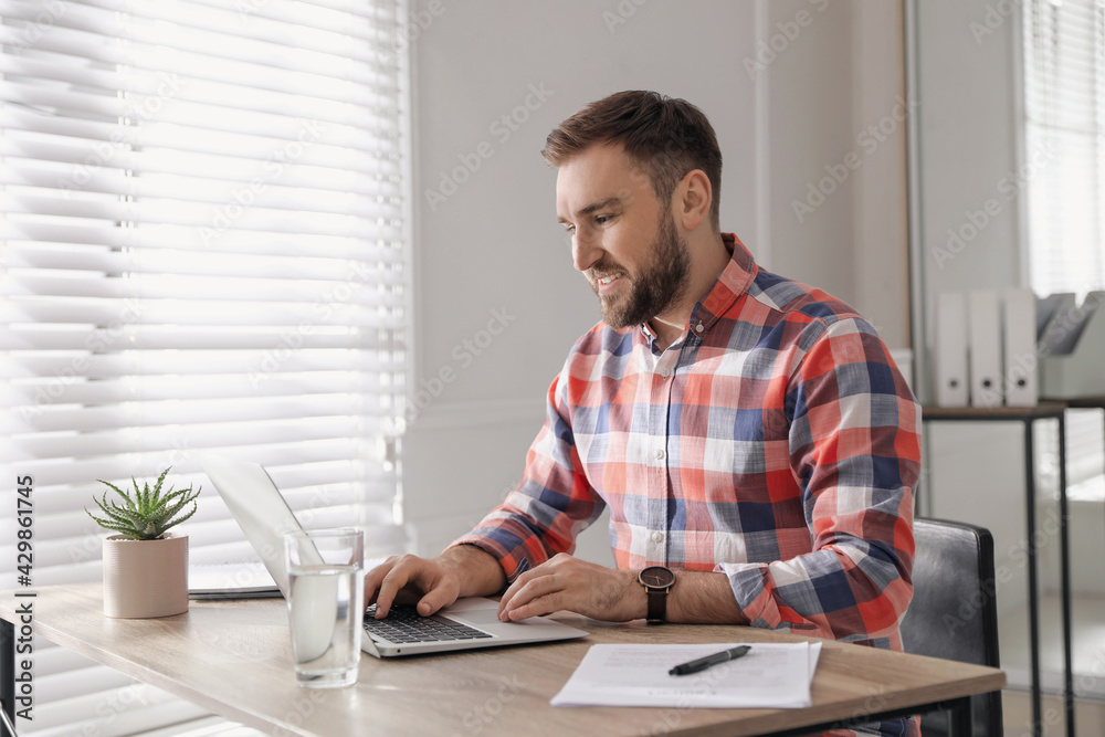 Young man working on laptop at table in office