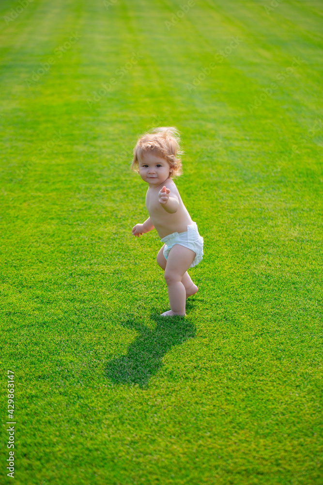 Cute funny laughing baby learning to crawl wearing a diaper having fun playing on the lawn watching summer in the garden. First step. Cute funny laughing baby learning to crawl wearing a diaper having fun playing on the lawn watching summer in the garden. First step.