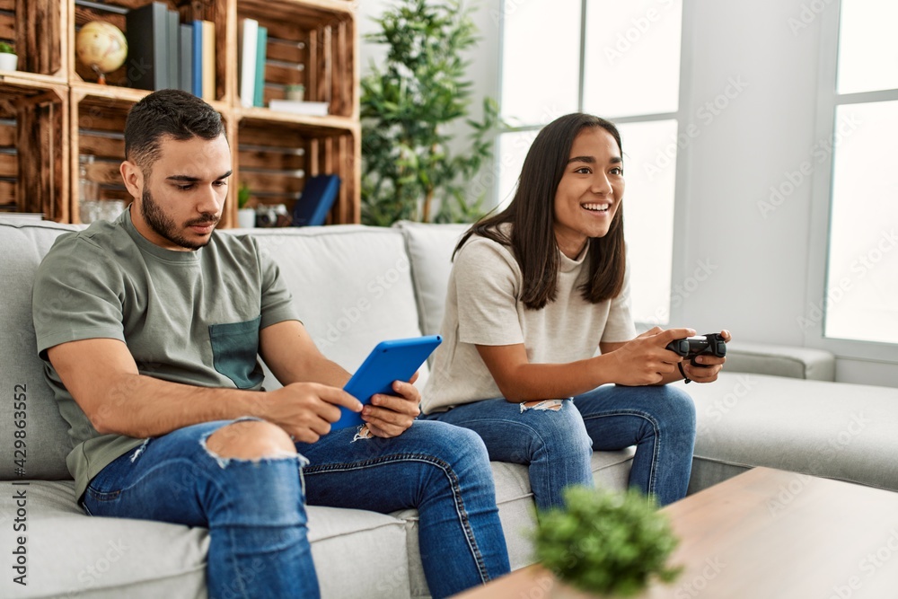 Young latin couple playing video game and using touchpad at home. Young latin couple playing video game and using touchpad at home.