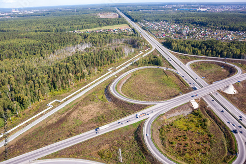 Aerial view of the highway. Road junction with traffic in summer. Photo of a highway from a drone. Motorway. Car passing. View from above.