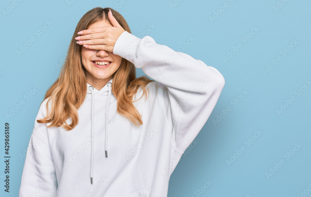 Beautiful young caucasian girl wearing casual sweatshirt smiling and laughing with hand on face covering eyes for surprise. blind concept.