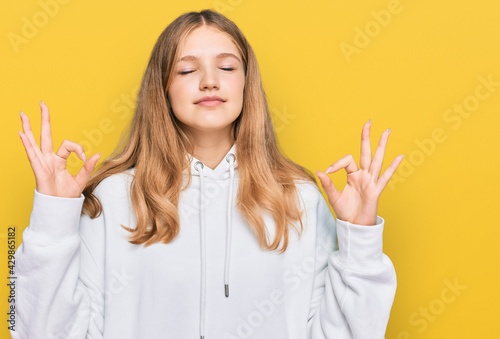 Beautiful young caucasian girl wearing casual sweatshirt relax and smiling with eyes closed doing meditation gesture with fingers. yoga concept.