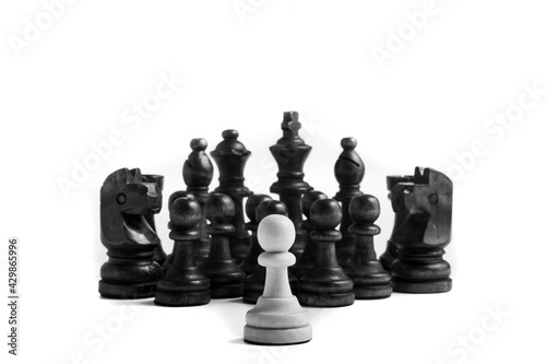 Un peón blanco se enfrenta a todas las piezas negras sobre fondo blanco