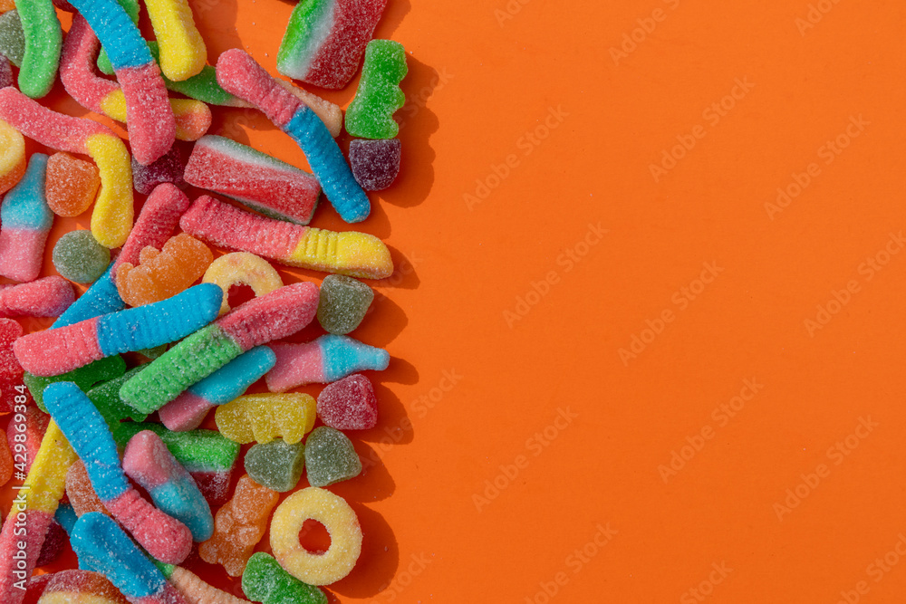 Colourful fizzy candies against an orange background 