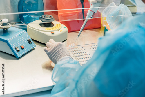 Scientist working at the laboratory. Life scientists researching in laboratory. Focused female science professional pipetting solution into glass cuvette.