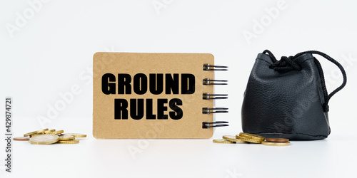 On a white background lies a bag with money, coins and a notebook with the inscription - GROUND RULES