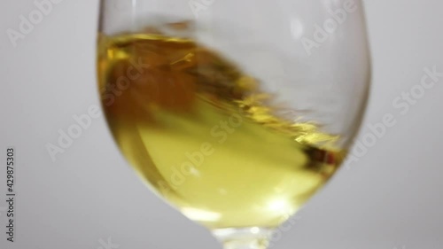 Waving white wine in a glass on white background.