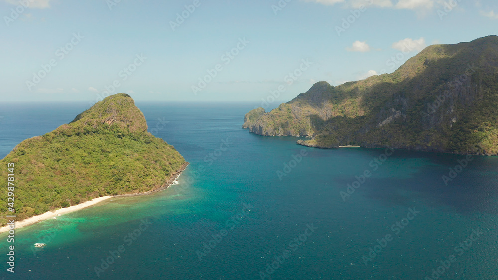 aerial view tropical beach on island with palm trees, blue lagoon and azure clear water. tourist boats on coast tropical island. Helicopter Island in El Nido, Palawan Philippines. Tropical landscape