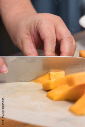 sharp knife chopping through a pile of canteloupe chunks