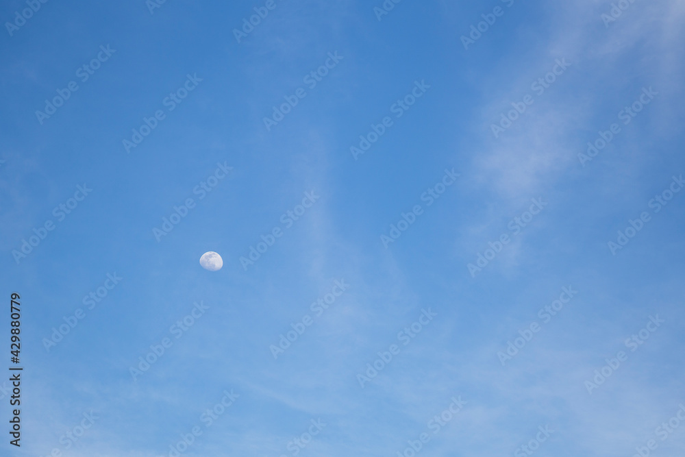 Luna viéndose en cielo azul con nubes Luna viéndose en cielo azul con nubes