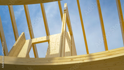 Canvastavla BOTTOM UP: Clear skies span over roof beams of a CLT house under construction