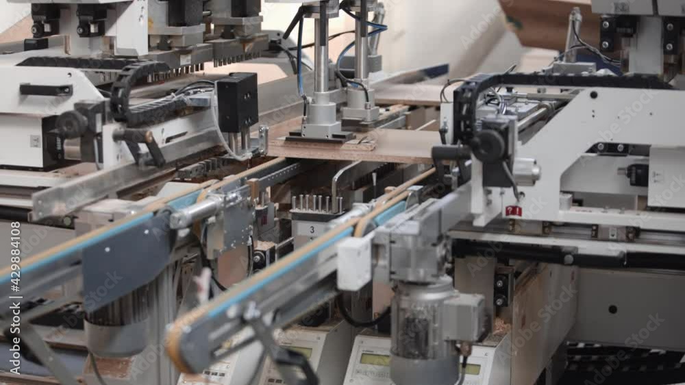 Conveyor machine for furniture production. Two employees of a furniture factory load blanks from chipboard Conveyor machine for furniture production. Two employees of a furniture factory load blanks from chipboard