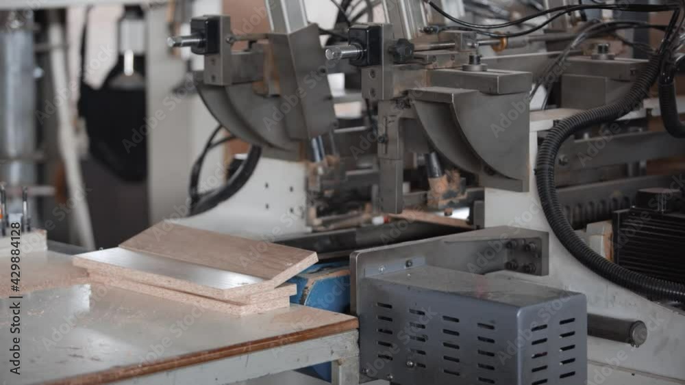 Conveyor machine for the production of furniture made of chipboard. Technological process of production automation. Close-up of working mechanisms Conveyor machine for the production of furniture made of chipboard. Technological process of production automation. Close-up of working mechanisms