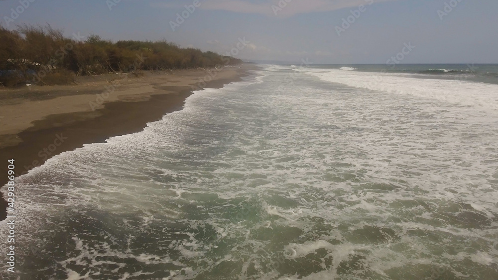 aerial view sandy beach near ocean with big waves at sunset time in tropical resort, Yogyakarta, Indonesia. seascape, ocean and beautiful beach. Travel concept. Indonesia, java