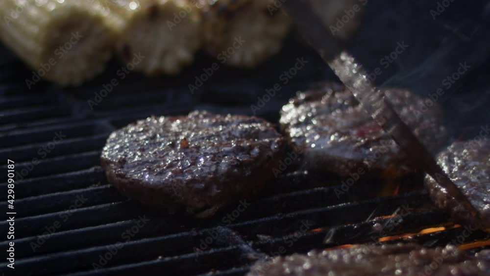 Close up shot of a char grilled burger being flipped at a cookout Close up shot of a char grilled burger being flipped at a cookout