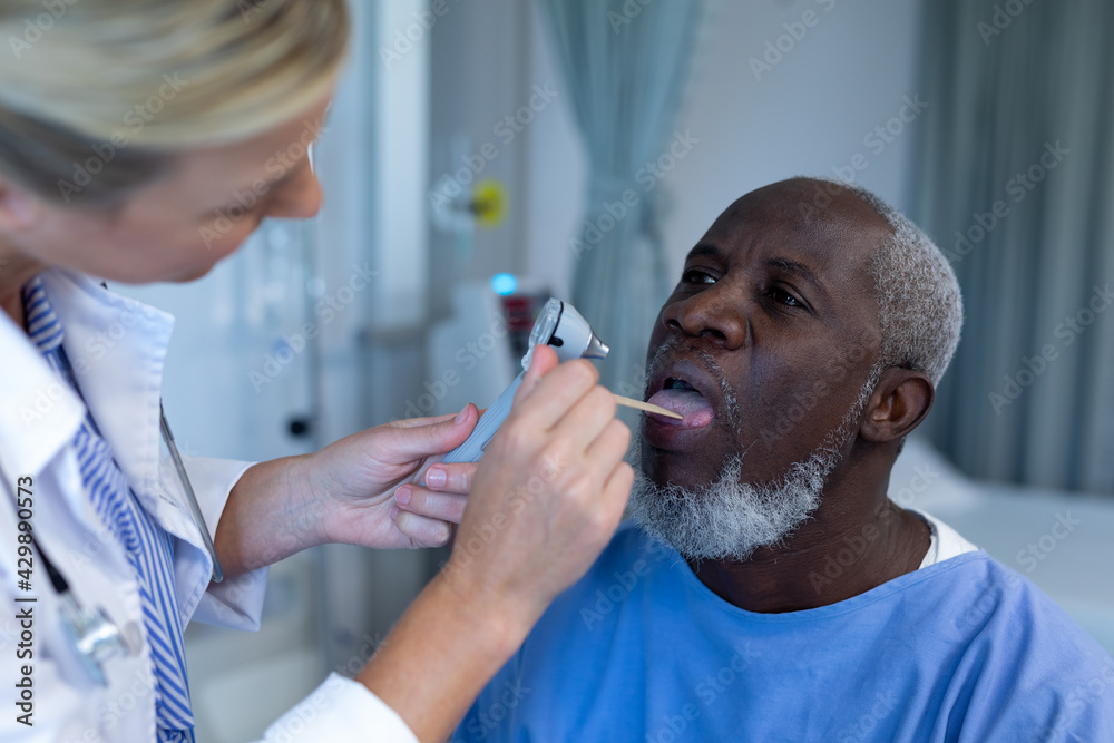Fototapeta premium Caucasian female doctor examining throat of african american male patient