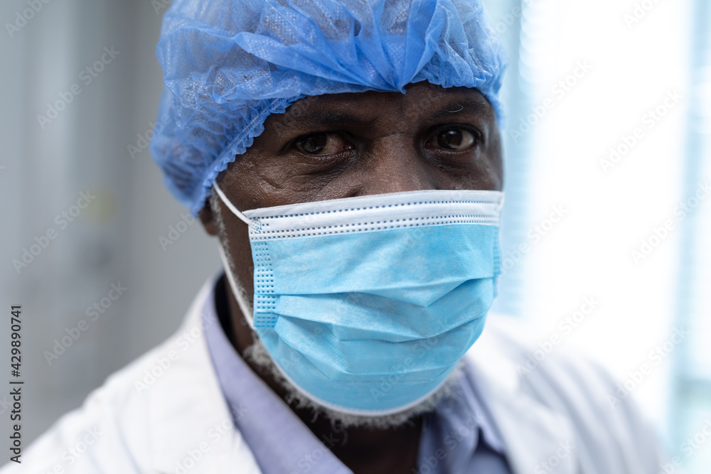 Portrait of african american male doctor wearing face mask and surgical cap looking to camera Portrait of african american male doctor wearing face mask and surgical cap looking to camera