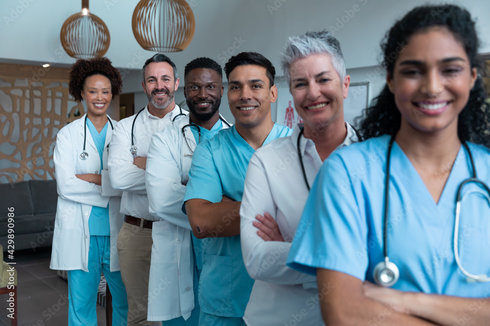 Portrait of group of diverse male and female doctors standing in hospital corridor smiling to camera Portrait of group of diverse male and female doctors standing in hospital corridor smiling to camera